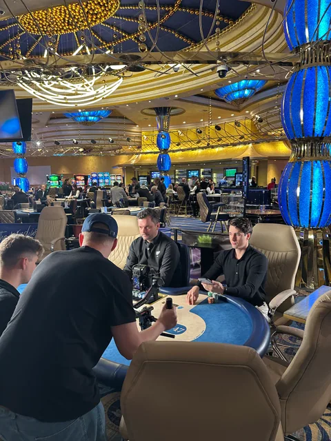 Kameraman s gimbalem natáčí dva účinkující u pokerového stolu.