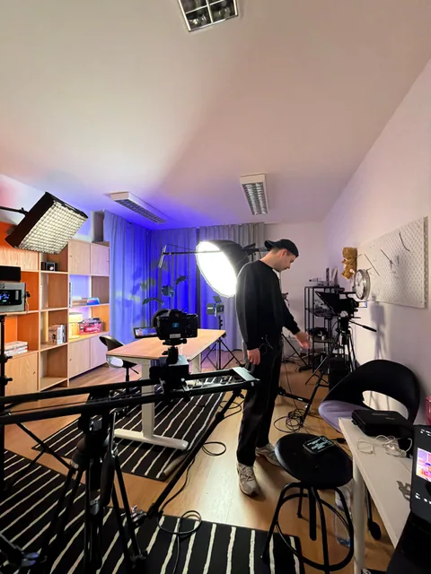 Člen štábu připravuje kameru, slider, světla a mikrofon ve studiu.